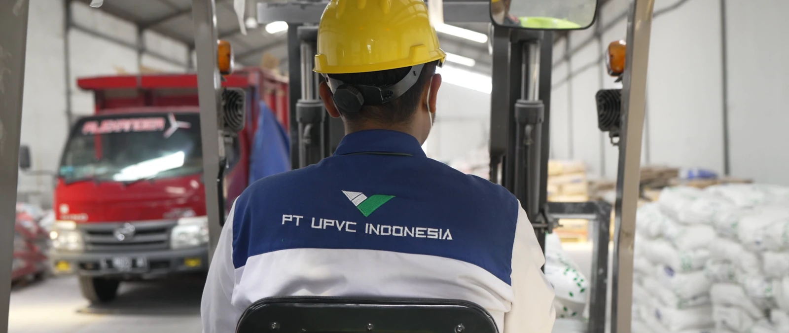 Operator forklift berseragam PT UPVC Indonesia di dalam gudang.